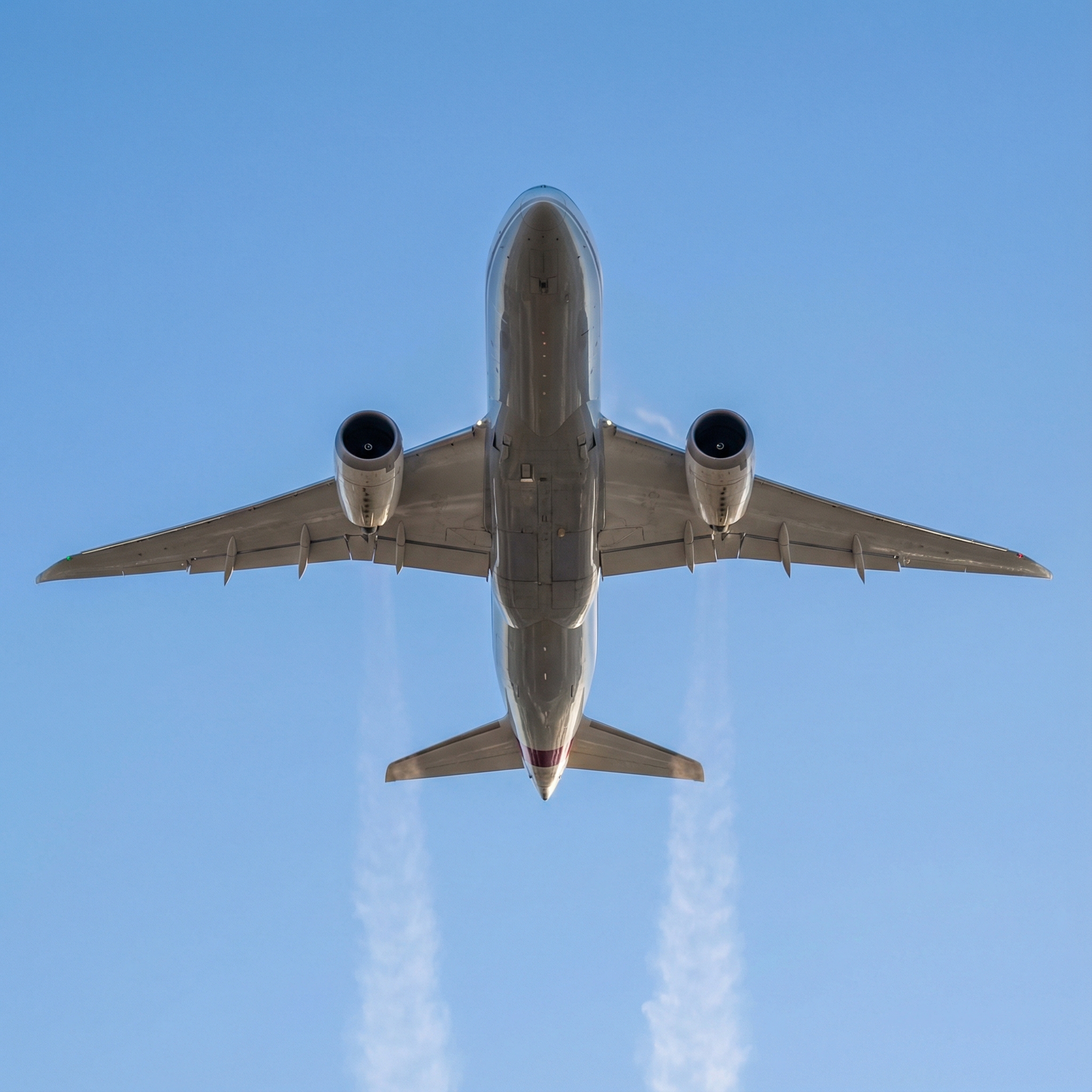 A sleek, modern passenger jet plane taking off into a clear blue sky, leaving a slight contrail. The perspective is from below, looking up, emphasizing its grand scale and speed. Informational style, 1:1 aspect ratio, no visible text.